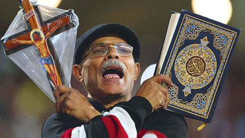 Một CĐV của đội tuyển Ai Cập cầm thánh giá và bản sao của Kinh Koran