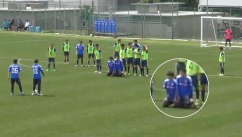 Hai cầu thủ của Mito Hollyhock quỳ xuống, chắn trước hàng rào Yokohama FC 
