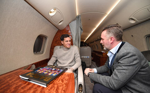 Coutinho ngồi trên máy bay, phía trước anh là quyển lịch sử của Barca