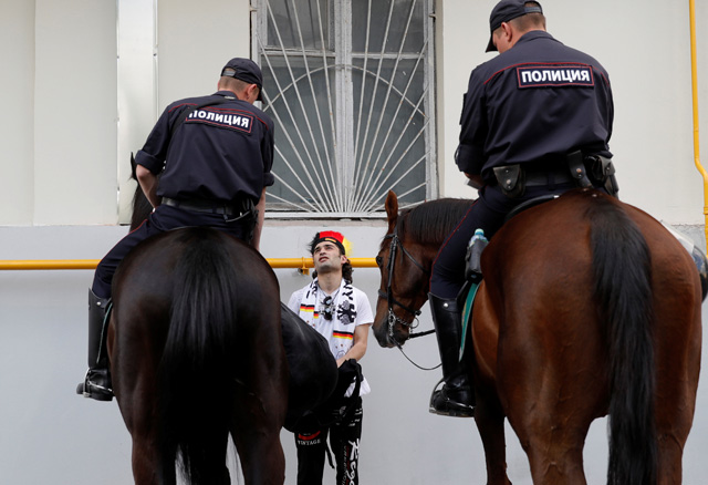 Hai cảnh sát cưỡi ngựa kiểm tra một CĐV khả nghi
