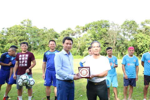 Tiến sỹ Nguyễn Việt Hòa trao kỉ niệm chương và Dụng cụ thi đấu thể thao cho ông Ngân Trung Sơn, Trưởng bản Đôn