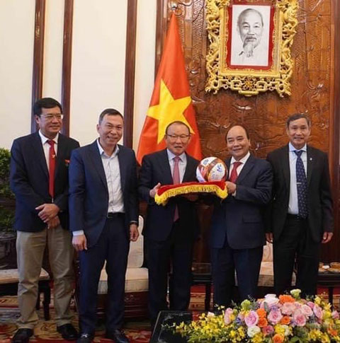 Chủ tịch nước Nguyễn Xuân Phúc chụp ảnh lưu niệm cùng Quyền Chủ tịch VFF Trần Quốc Tuấn và các HLV Mai Đức Chung, Park Hang Seo 	 Ảnh: VietnamPlus