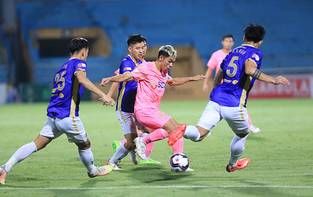 Văn Triền (áo sáng) tả xung hữu đột trong vòng vây các cầu thủ Hà Nội FC - Ảnh: Minh Tuấn