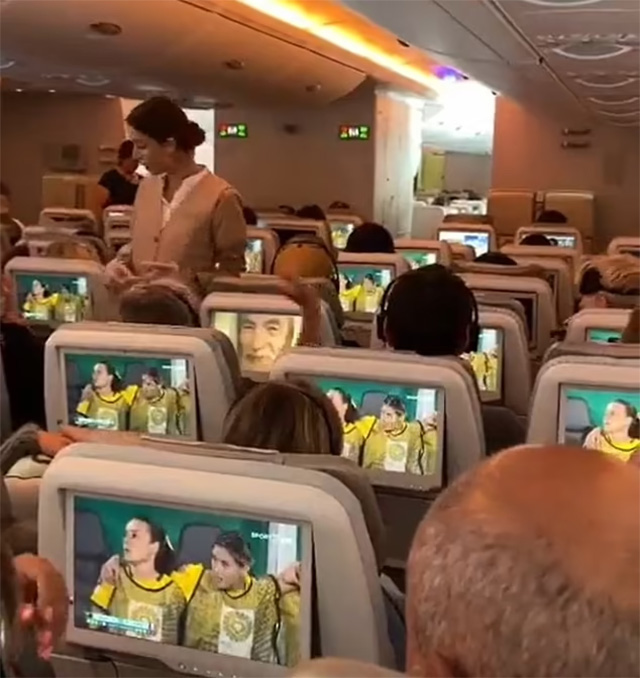 Một hành khách xem phim trên máy bay trong khi những người thưởng thức bóng đá