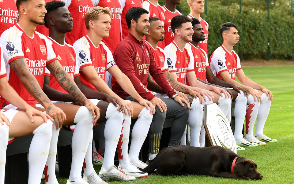 Cả đội Arsenal chụp hình với chú chó có tên "Chiến thắng"