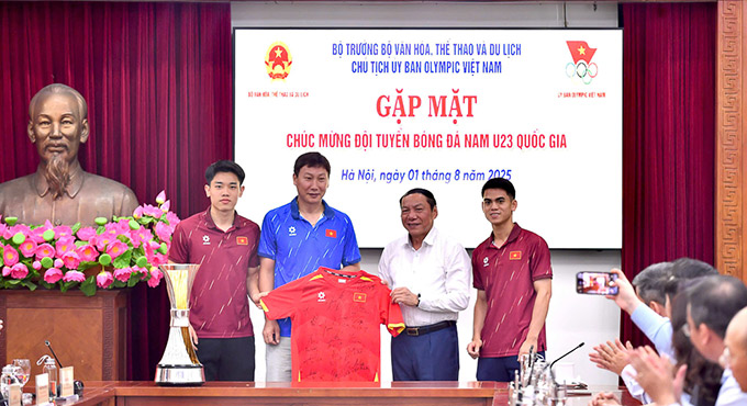 HLV Kim Sang Sik và các cầu thủ trao tặng Bộ trưởng Nguyễn Văn Hùng áo thi đấu có chữ ký của toàn đội. Ảnh: Đăng Huy