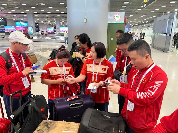 Các thành viên đoàn thể thao Việt Nam lấy hành lý tại sân bay - Ảnh: Bùi Lượng