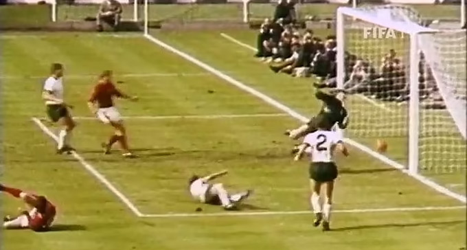 Hurst (áo đỏ bên trái) ngã xuống sân sau khi dứt điểm