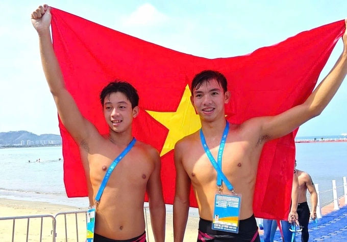 Nguyễn Huy Hoàng (phải) và Mai Trần Tuấn Anh ăn mừng sau khi hoàn tất nội dung bơi biển 5km - Ảnh: VASA